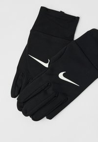 Zwarte Nike-handschoenen met witte swoosh-logo's, geplaatst op een lichtgrijze achtergrond, waarbij beide handschoenen met uitgelijnde vingers zijn te zien.