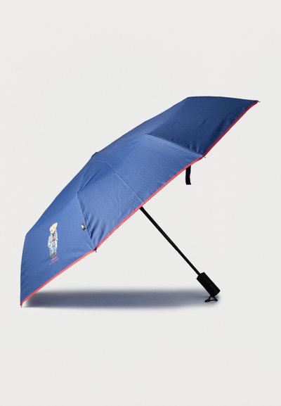 Μπλε ομπρέλα με κόκκινα διακοσμητικά, με σχέδιο καρτούν αρκούδας. Μαύρη λαβή και μεταλλικό πλαίσιο, υφή υφάσματος ομαλή και ανθεκτική.
