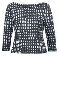 Haut à motifs noir et blanc avec des manches trois-quarts, un col arrondi et une silhouette boîte. Fabriqué à partir d'un tissu lisse et extensible.