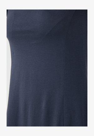 Navy blauwe aansluitende top gemaakt van zacht, gladde stof; heeft een zachte ronding en stiksel details voor een geklede look.