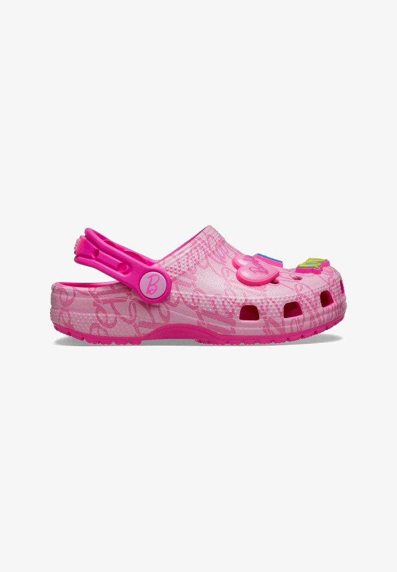 Sabot rose pour enfant avec bride de talon réglable et breloques décoratives en forme de cœur et colorées sur le dessus, avec une surface à motifs.