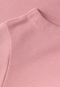 Jasnoróżowy T-shirt z materiału o prążkowanej fakturze i okrągłym dekoltem. Materiał wydaje się miękki z delikatnym naciągiem i równomiernym szwem.