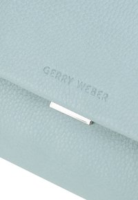 Hellblaues Leder-Clutch von Gerry Weber mit strukturierter Oberfläche und einem silberfarbenen Metallschloss. Eingestanztes Logo auf der Vorderseite.