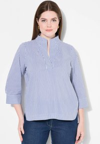 Blusa a righe blu e bianche con bottoni parziali e maniche a tre quarti. Realizzata in tessuto leggero, presenta spacchi laterali e una vestibilità comoda.