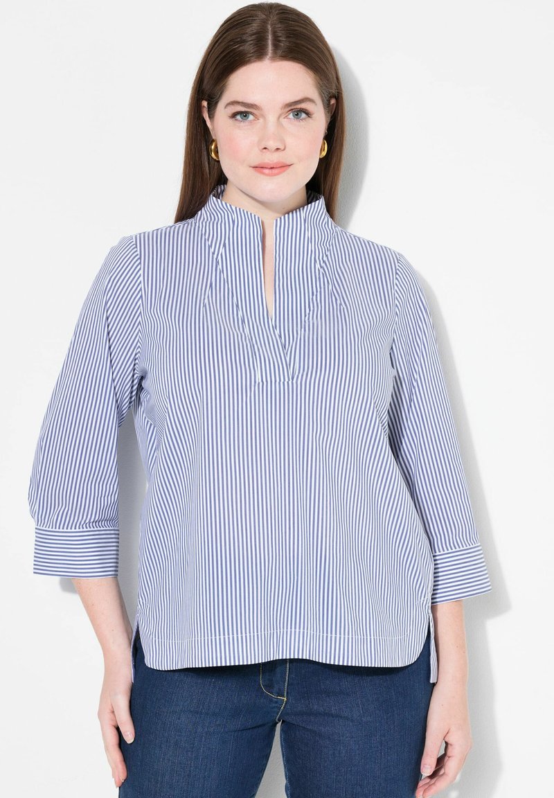 Blusa a righe blu e bianche con bottoni parziali e maniche a tre quarti. Realizzata in tessuto leggero, presenta spacchi laterali e una vestibilità comoda.