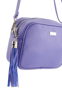 Lila Leder-Crossbody-Tasche mit strukturiertem Finish, silbernen Beschlägen, Reißverschluss und einem blauen Troddelakzent auf einer Seite.