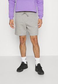 Grå bomullsshorts med elastisk midja och dragsnöre. Vit Adidas-logga på vänster ben. Matchas med svarta sportskor och vita strumpor.