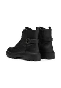 Bottines noires en cuir avec un design structuré, à lacets à l'avant, fermeture éclair sur le côté et semelle en caoutchouc épaisse avec des rainures profondes.