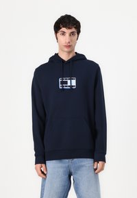 Felpa blu navy in misto cotone con tasca frontale e cappuccio con coulisse. Presenta un logo grafico in bianco e azzurro.