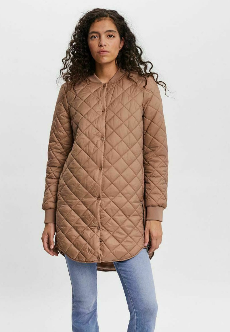 Quilted long brown jacket with a rounded neckline, front buttons, and side pockets. Features ribbed cuffs and a smooth finish.