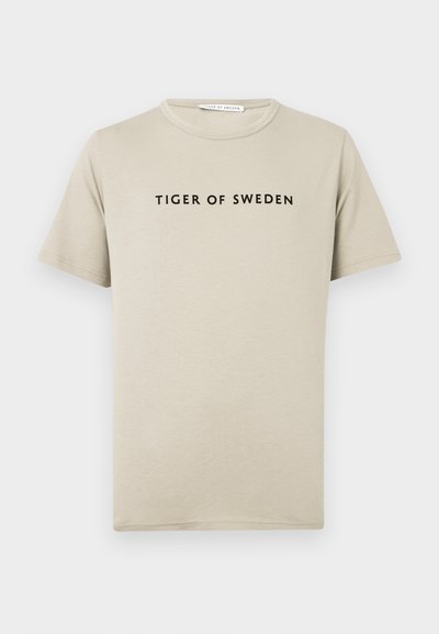 Svetlá béžová bavlnená tričko s krátkymi rukávmi, okrúhlym výstrihom a čiernym textom "TIGER OF SWEDEN" potlačeným centrálne na prednej strane.