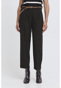Black pleated trousers with a high waist, accompanied by a braided brown belt. The outfit is paired with glossy, dark purple ankle boots.