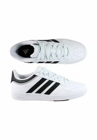 Sneakers bianchi con strisce nere, realizzati in pelle liscia. Punta tondeggiante, dettagli perforati e suola in gomma. Presentano il marchio Adidas.