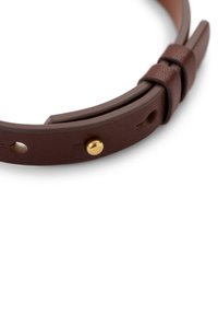 Brunt lærarmbånd med en strukturert overflate, justerbar stroppe med detaljer i gullfarget metall, og et minimalistisk design.