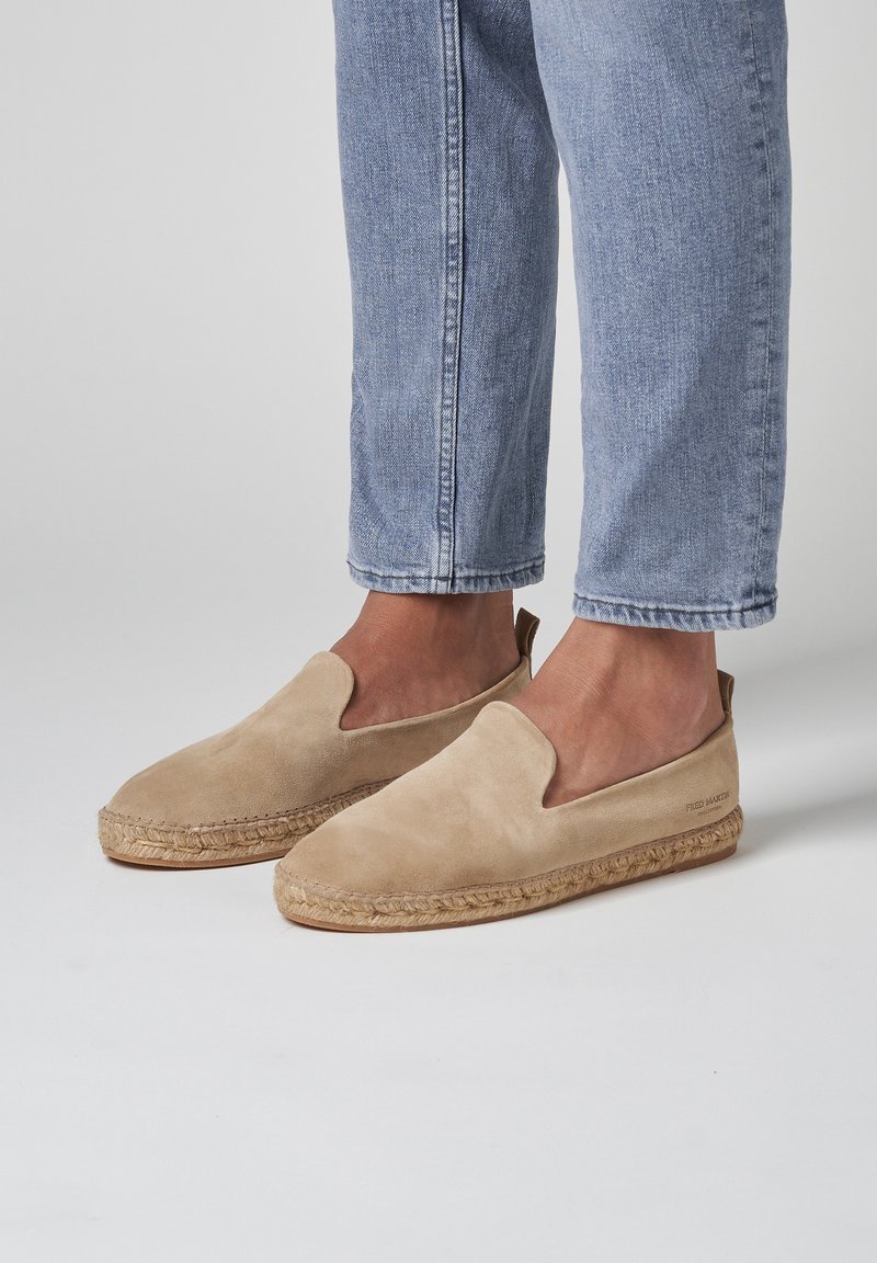 Beige suedine espadrillos med en vævet jute-sål, der har sideudskæringer og en glat finish, parret med lyseblå cropped jeans.