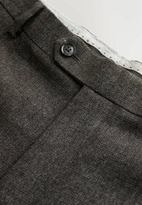 Dark gray textured trousers with a button closure, featuring a subtle pattern and a white houndstooth lining at the waistband.