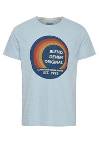 Šviesiai mėlynas trumpomis rankovėmis marškinėliai, pagaminti iš medvilnės, su apvaliu grafiniu dizainu raudona, geltona ir mėlyna spalvomis bei tekstu: "BLEND DENIM ORIGINAL."