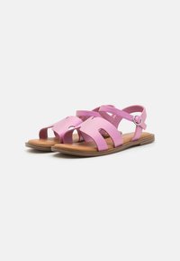 Rosa sandaler med utskärning, justerbar ankelrem och brun sula. Slät syntetisk material med platt fotbädd för komfort.
