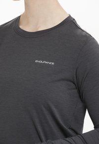 Dunkelgraues Langarmshirt aus leichtem Material, mit Rundhalsausschnitt und weißem "ENDURANCE"-Logo auf der Vorderseite.