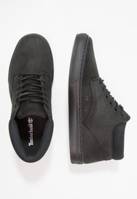 Mustat nahkakengät, joissa on pyöreä kärki, nauhakiinnitys edessä ja teksturoituja paneeleja. Varustettu matalla pinnalla ja pehmustetulla kauluksella mukavuutta varten.