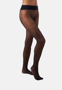 Collants noirs transparents avec une taille échancrée, texture lisse et design ajusté, s'étendant de la taille aux orteils avec une finition semi-transparente.