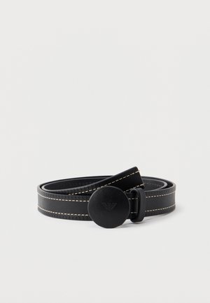 Black leather belt with white stitching and round buckle featuring embossed eagle logo, coiled on white background.