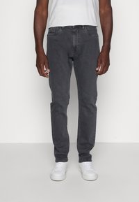Jeans grises de corte recto, fabricados en denim, con cinco bolsillos y un lavado sutil. Combinados con zapatillas blancas.