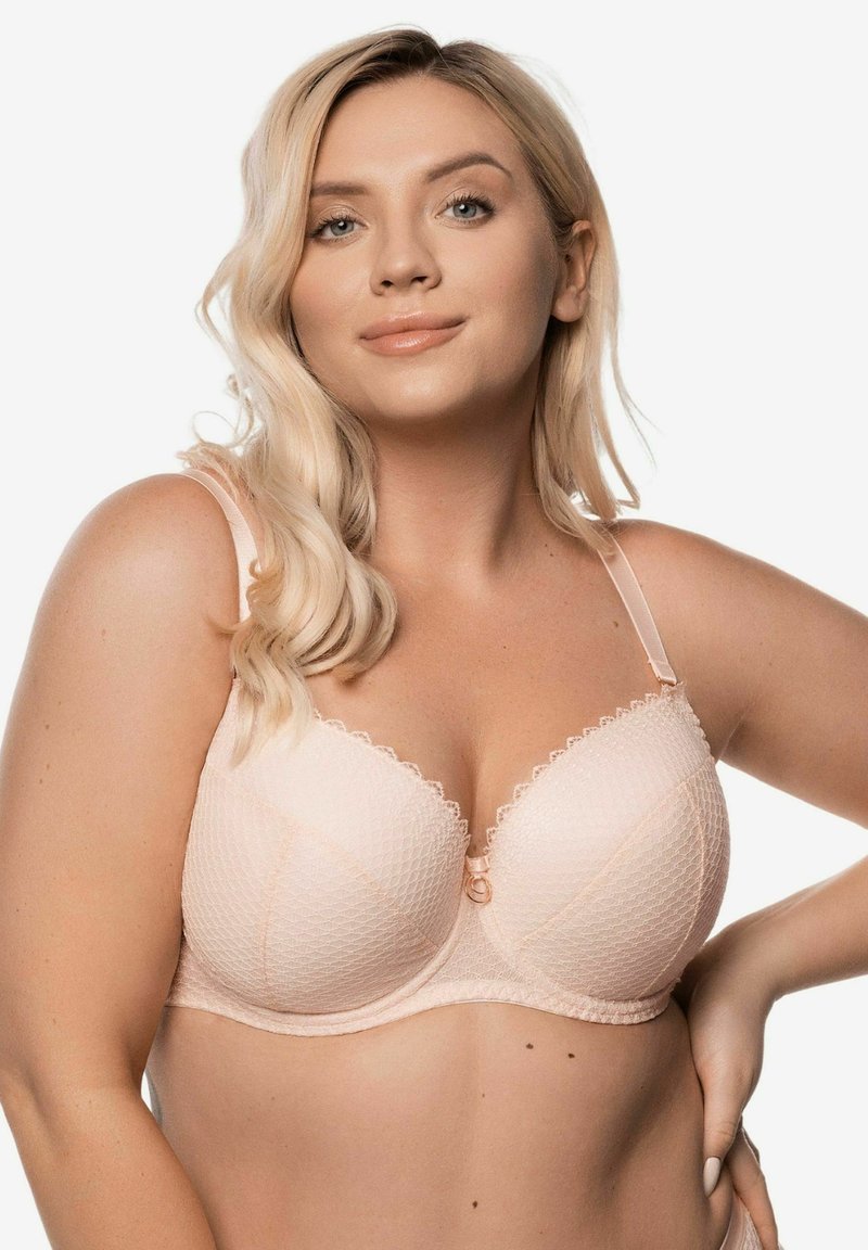 Jasnoróżowy stanik o strukturalnym fasonie, teksturowanej tkaninie, falbaniastych krawędziach oraz małym dekoracyjnym akcentem na środku. Widoczne regulowane ramiączka.