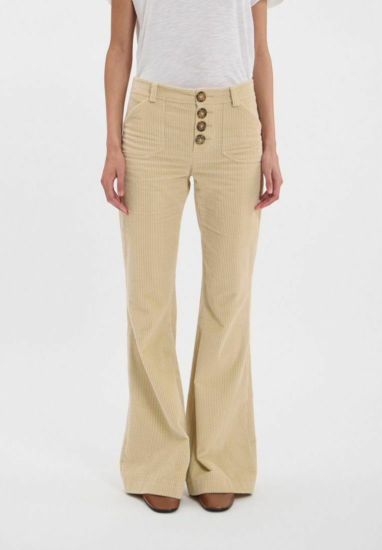 Pantalons évasés en velours côtelé beige avec une taille haute, cinq poches et quatre boutons en laiton à l'avant. Tissu texturé avec des lignes verticales.