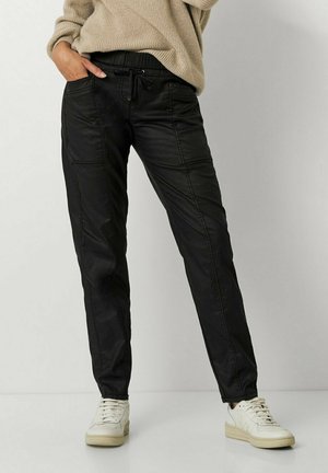 Pantalons noirs à taille élastique en matériau lisse, avec des poches latérales, un cordon de serrage et une coupe fuselée.