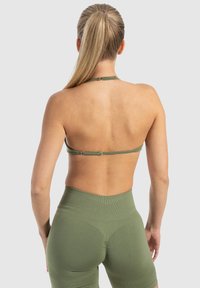 Olijfgroene halter sportbeha met dunne banden. Hooggepaste, aansluitende bijpassende shorts met ribbelstructuur en een naadloos ontwerp.