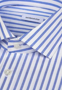 Camicia a righe blu e bianche realizzata in tessuto liscio. Presenta un colletto standard, chiusura con bottoni e dettagli di cuciture sottili. Etichetta del marchio visibile.