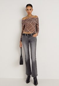 Ανοιχτός στον ώμο, καφέ καρό τοπ με μακριά μανίκια; ψηλόμεσο, καμπάνα γκρι τζιν; μαύρη ζώνη; μαύρη τσάντα; λαμπερές μαύρες μπότες.