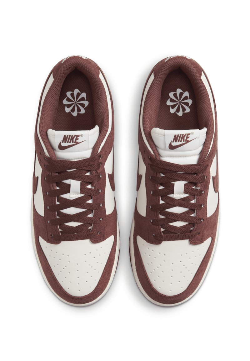 Zapatillas Nike en blanco y burdeos, con una parte superior de ante, cierre de cordones, puntera perforada y un logo en la lengüeta y en la plantilla.