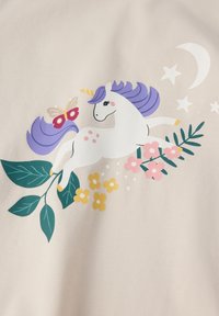 Witte eenhoorn met paarse manen en staart, gele hoorn, omringd door groene bladeren, roze en gele bloemen, een vlinder, sterren en een halve maan.
