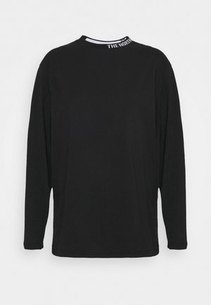 Camiseta negra de manga larga con cuello redondo y texto blanco sutil "THE NORTH" en el interior del cuello, mostrada sobre un fondo blanco.