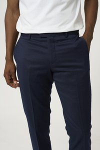 Pantalones tailored de color azul marino, fabricados con un tejido suave, que presentan una parte delantera plana, bolsillos laterales y un diseño de corte ajustado.