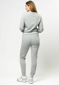 Grijze sweatshirt en bijpassende joggers, katoenen mix, getailleerd ontwerp, geribde manchetten en tailleband, gecombineerd met witte en beige sneakers.