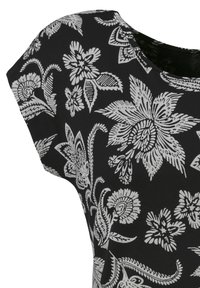 Melna topiņa ar ziedu rakstu, kurā ir balti sarežģīti ziedu un lapu dizaini. Mīksts, elastīgs audums. Apa�ļa kakla izgriezums ar piegrieztiem piedurkņu galiem.