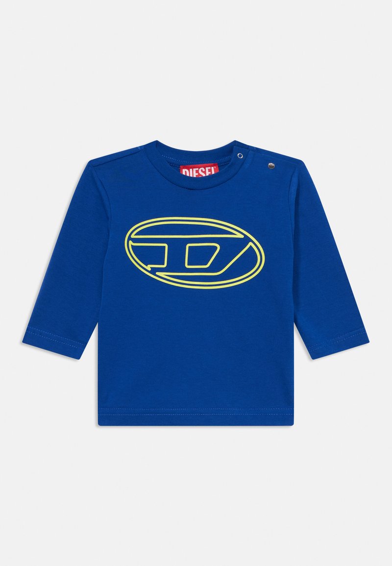 Kék, hosszú ujjú pamut póló, kerek nyakkivágással. Elöl egy sárga ovális logóval rendelkezik. A vállnál patentgombos részletezéssel készült.