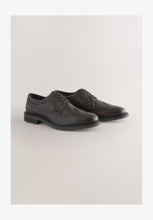 Pruunid nahast brogues kingad tekstuurse viimistlusega, kaunistatud dekoratiivsete soonte ja ümmarguse varbaga. Voolujooneline must kummist tallaosa haarduvuse tagamiseks.