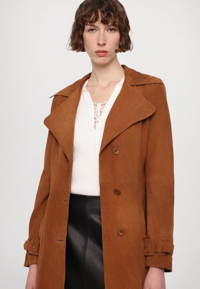 Cappotto trench in suede marrone con design doppiopetto, ampi revers e cintura regolabile. Presenta una texture liscia e una leggera lucentezza.