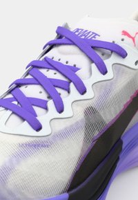 Chaussure de sport violet et blanc dotée d'un dessus texturé, de lacets plats et d'une semelle rembourrée avec un motif en vagues ainsi qu'un logo "ULTRAVIRAVE".