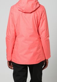 Korallrosa vattentät jacka med huva, texturerat tyg och en något figursydd silhuett. Har en rak nederkant och sidfickor.