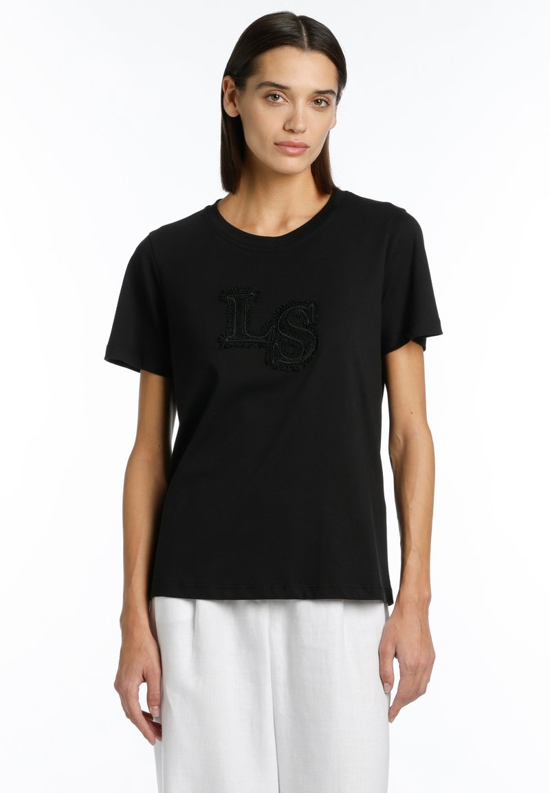 Black cotton t-shirt with a round neckline and short sleeves. Features a textured black "LS" logo on the front. Smooth fabric; relaxed fit.