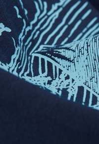 Primer plano de una tela azul oscura con patrones de líneas abstractas en azul claro que crean un efecto visual texturizado y en capas.