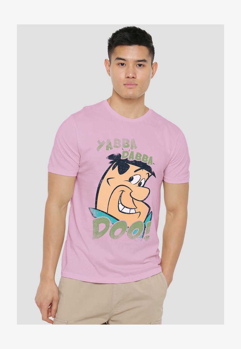 Young man wearing a pink t-shirt with a smiling animated character and the text "YABBA DABBA DOO!" on the front.