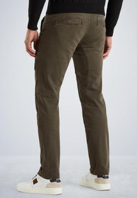 Pantalons cargo en coton vert olive avec poches arrière, jambes fuselées et détails de couture visibles, associés à des baskets blanches.