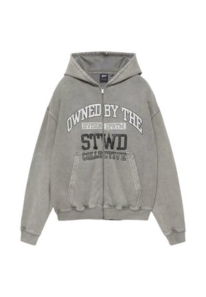 Felpa grigia con cappuccio e zip frontale, tasche anteriori e testo bianco e nero con la scritta "OWNED BY THE DIVISION DPRTM. STWD COLLECTIVE."