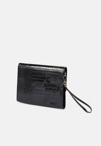 Cartera de mano negra con estampado de cocodrilo y acabado brillante, cuenta con una correa para la muñeca y acentos en dorado. Forma rectangular compacta.